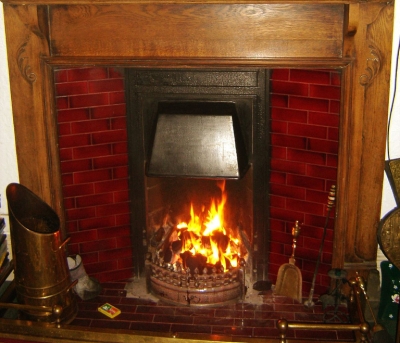 Fireplace with tiled hearth and surround, steel hood, brass scuttle, fender etc.